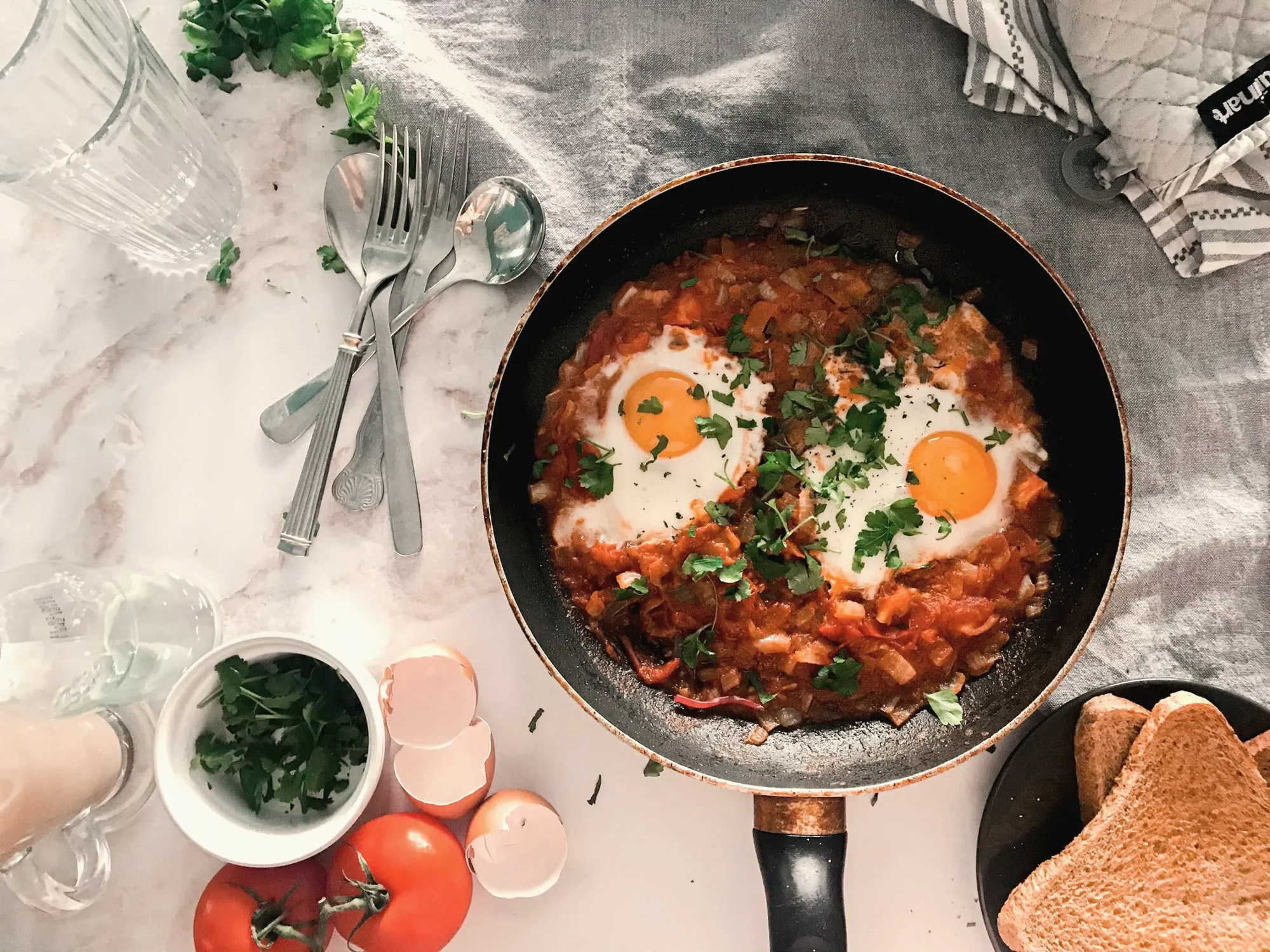 Eggs baked in spiced tomato sauce in a pan, with toast on the side
