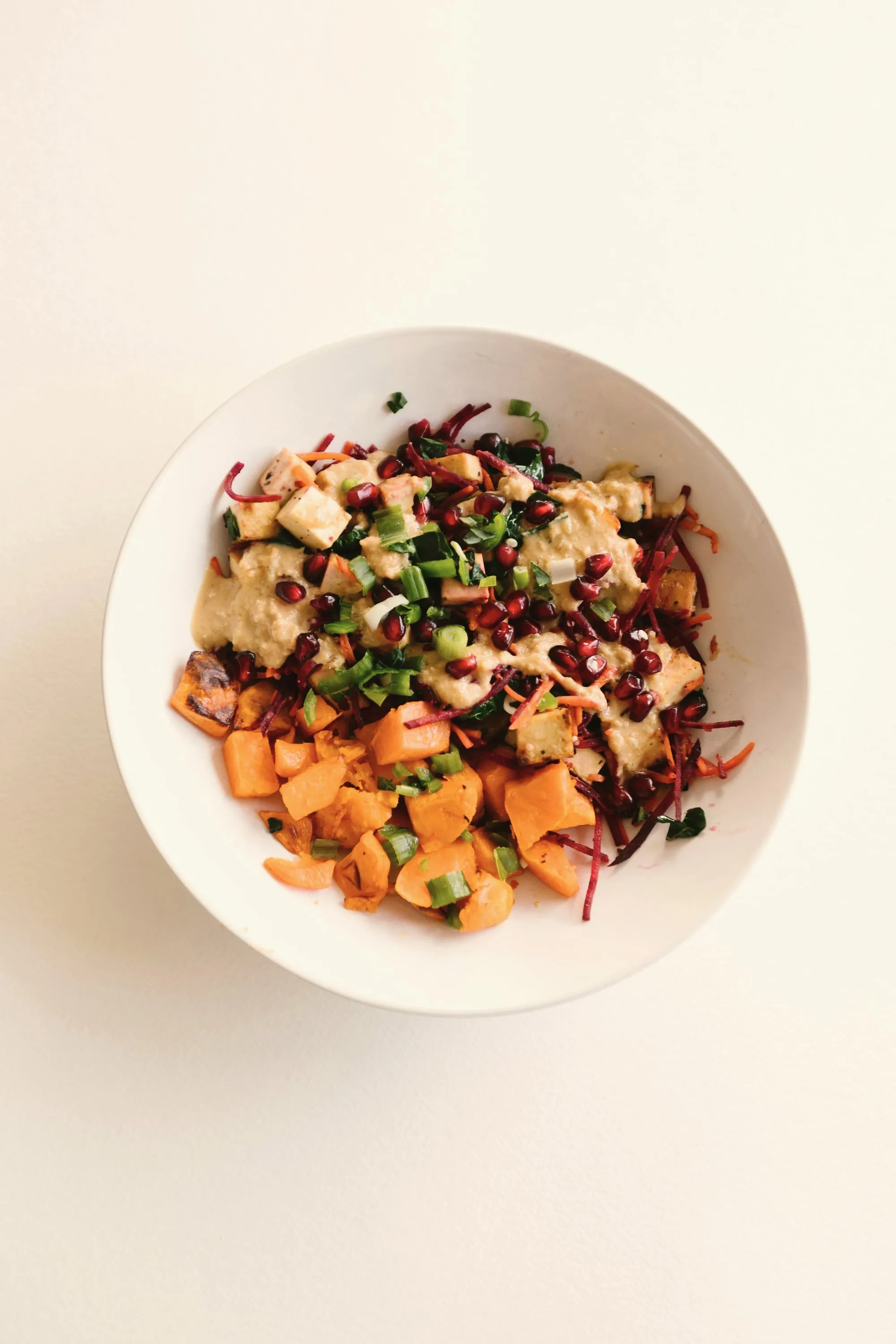 A bowl of roast squash, grains, pomegranate and greens