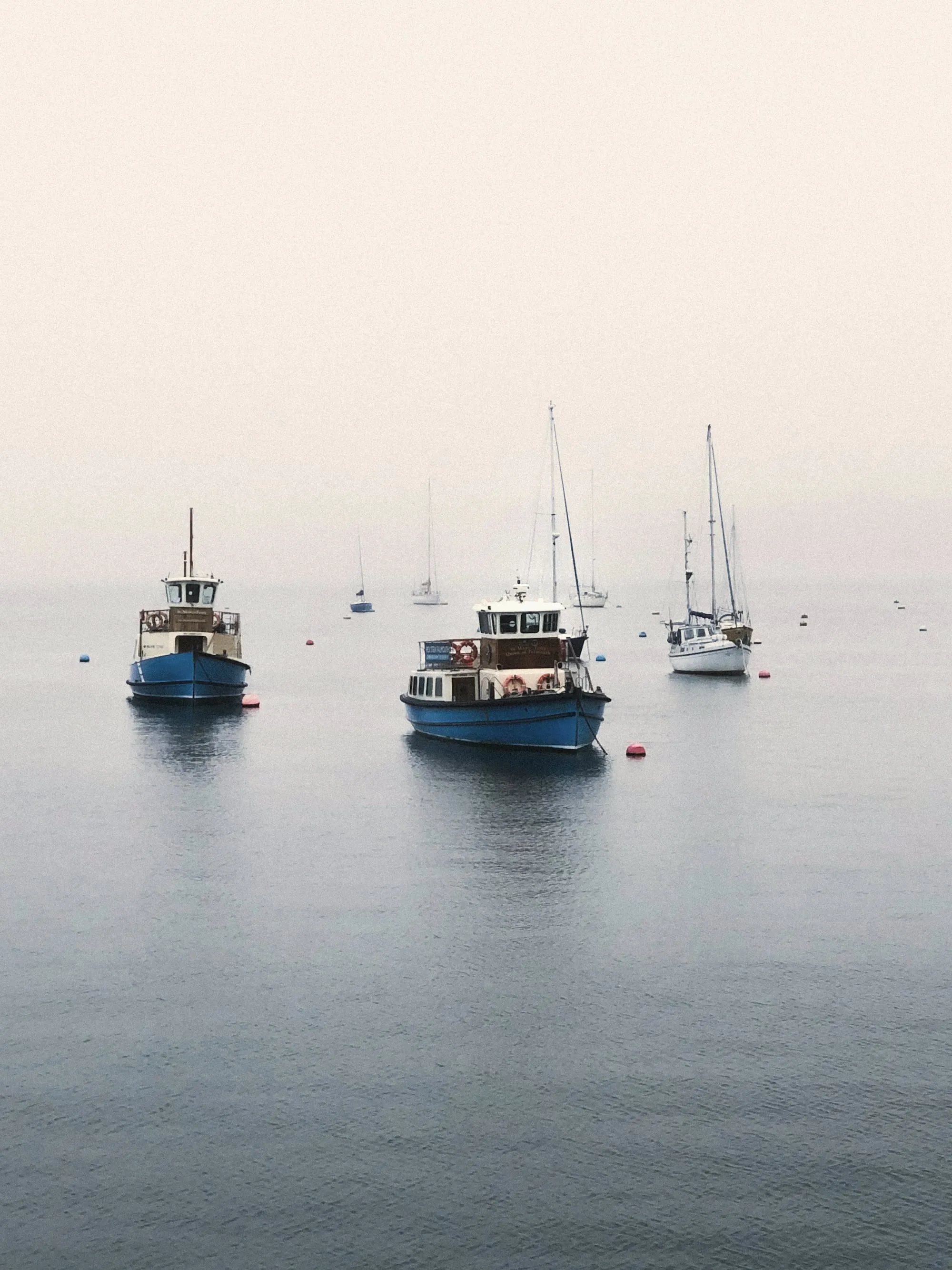 Small boats moored on a calm, misty harbour in the morning
