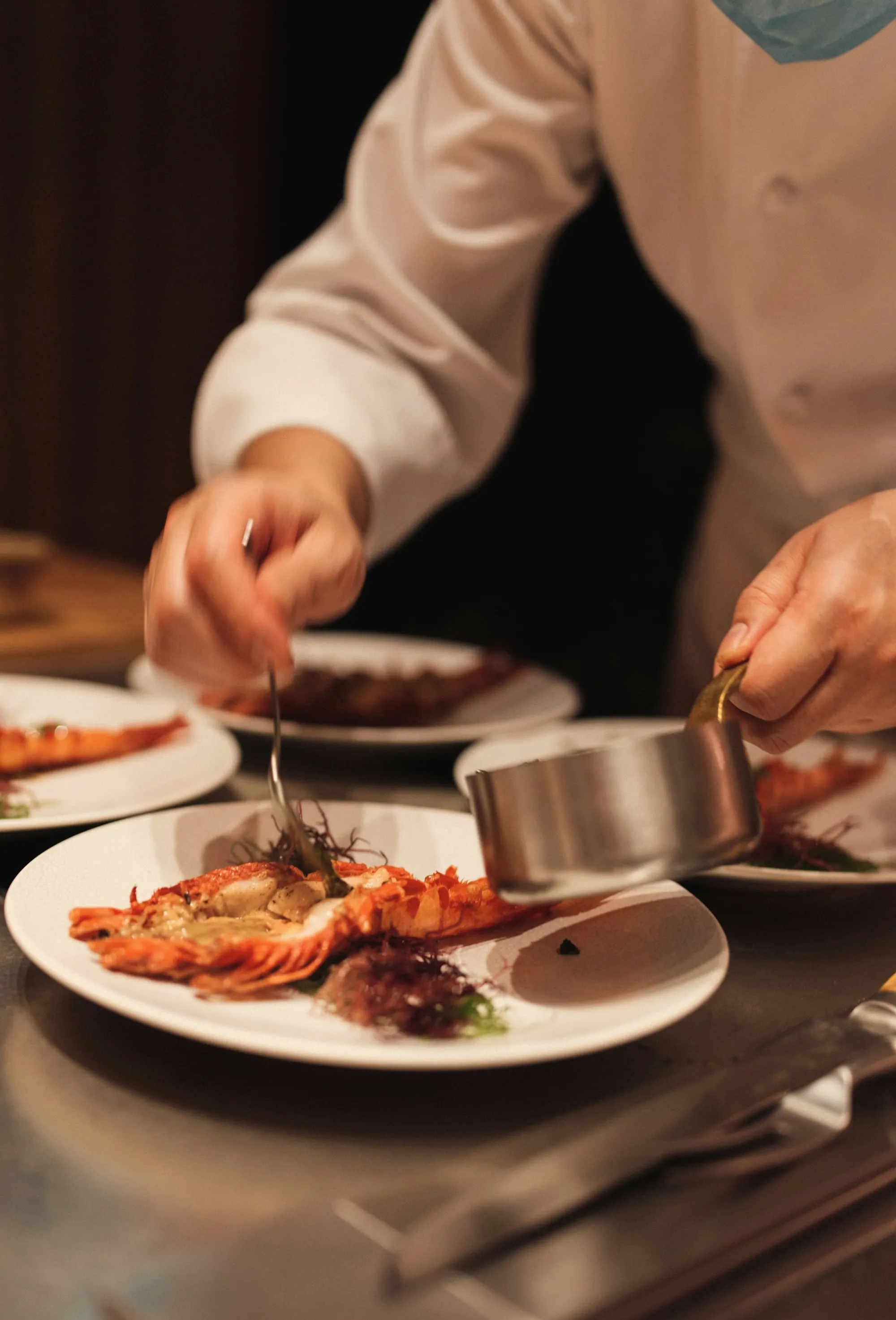 A cook's hands plating up a dish in the kitchen